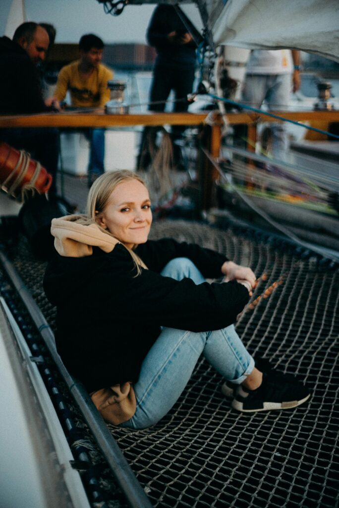 Young woman sitting on a sailboat enjoying a calm evening with friends.