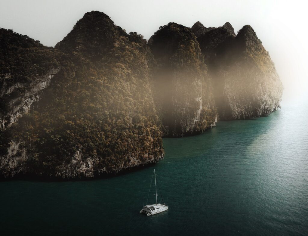 Stunning aerial view of limestone cliffs and sailboat in Krabi, Thailand.