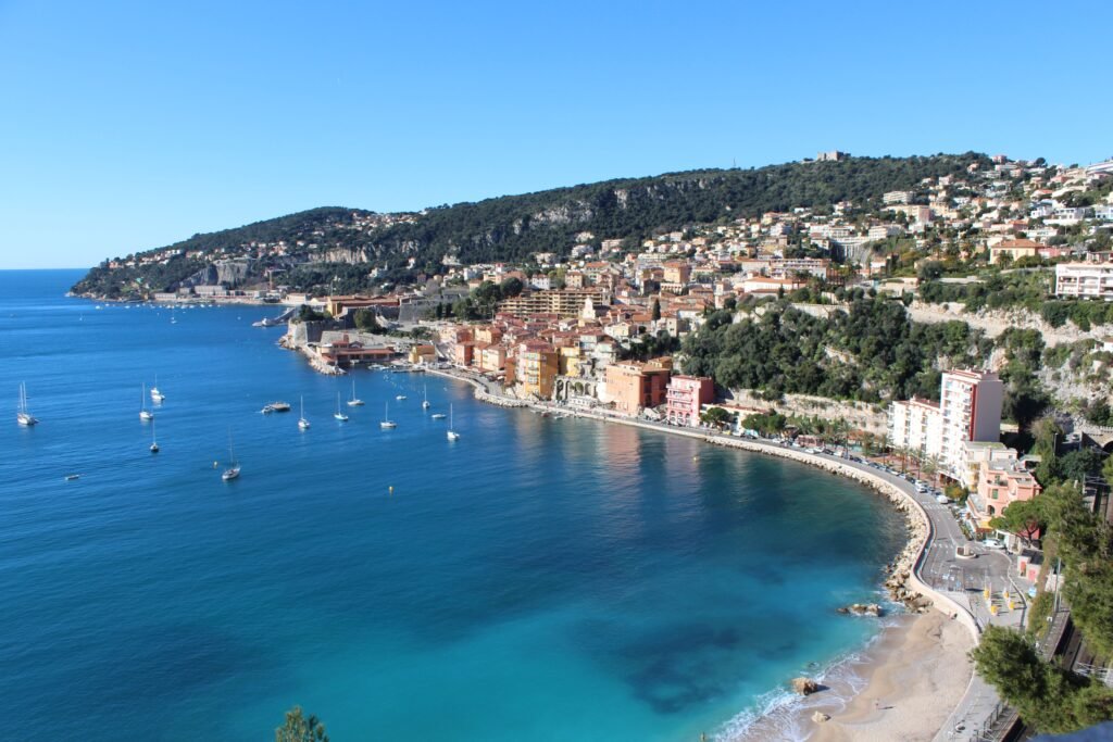Stunning aerial view of Villefranche-sur-Mer with coastline and boats on a clear summer day.