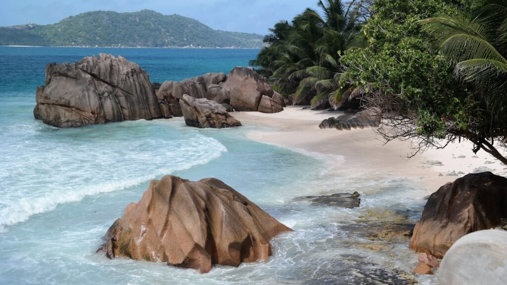 Serene tropical beach with unique rock formations and lush palm trees.