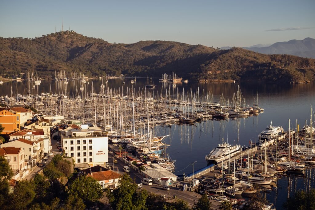 Aerial shot of Fethiye marina with moored sailboats and picturesque mountains at sunset.