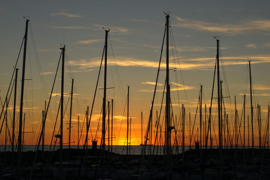 A tranquil sunset scene with silhouetted sailboat masts at Lido di Ostia, Lazio, Italy.
