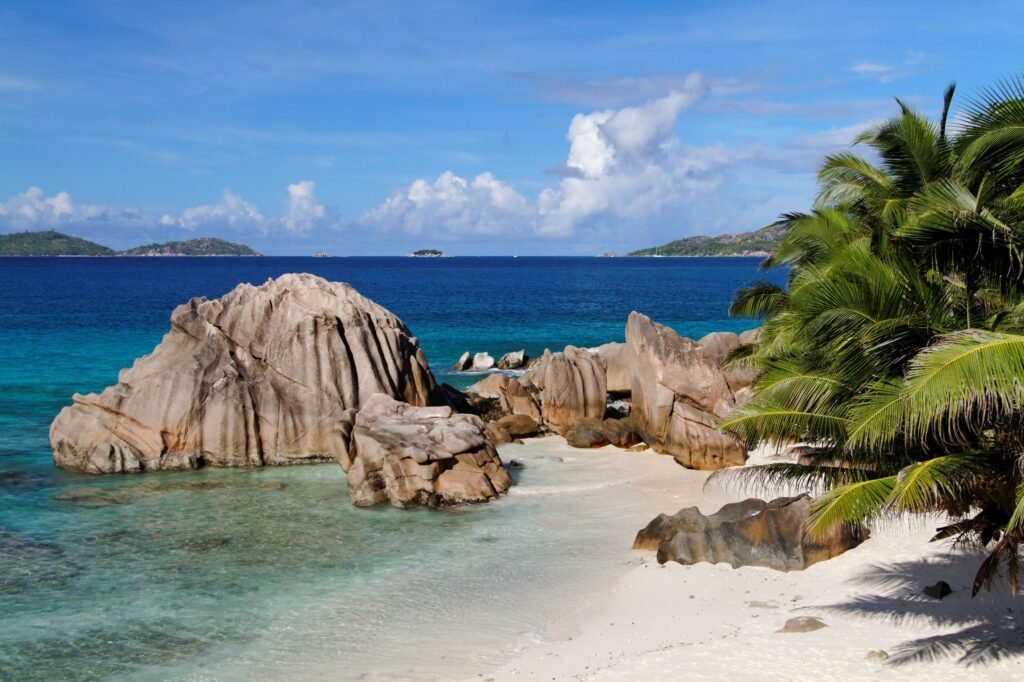 Idyllic tropical beach on La Digue, Seychelles, featuring granite rocks, palm trees, and turquoise waters.